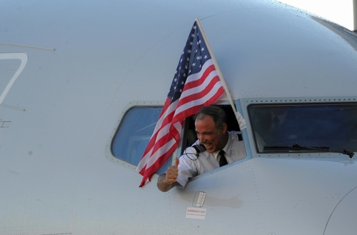 خلبان هواپیمای آمریکایی بعد از فرود در فرودگاه هاوانا پرچم آمریکا را از پنجره کابین خارج کرد و تکان داد. این نخستین پرواز مسافری میان شهر میامی امریکا و هاوانا کوبا بعد از 50 سال بود/ خبرگزاری فرانسه
