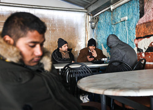پناهجویان افغان و پاکستانی در حال شارژ کردن گوشی های تلفن شان در یک کافه در شهر تسالونیکی یونان