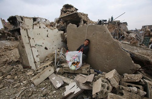 یک پسربچه سوری اسباب بازی هایش را از خانه ویران شده بیرون کشیده است- حلب