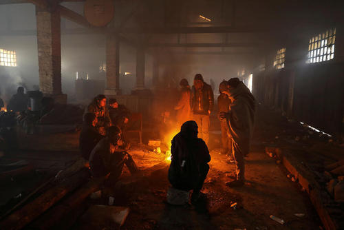 گرم شدن پناهجویان در داخل اردوگاهی در هوای سرد شهر بلگراد صربستان