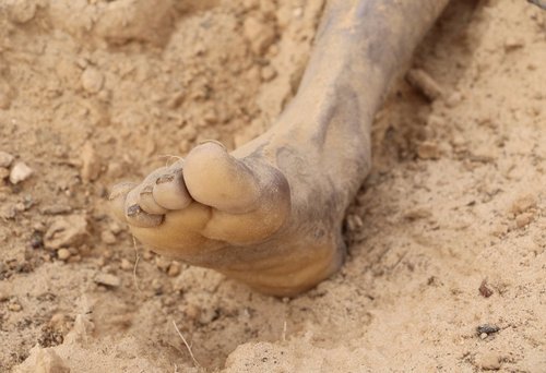 بیرون کشیدن بدن یک پناهجوی دفن شده در شن های سواحل لیبی