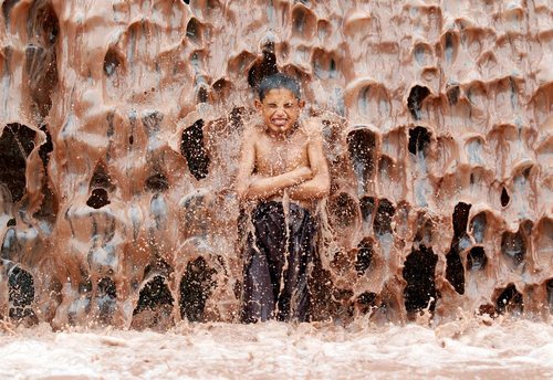 خنک شدن یک نوجوان افغان زیر آبشاری گل آلود در شهر جلال آباد افغانستان