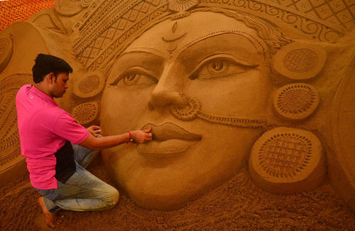 هنرمند هندی در حال درست کردن مجسمه شنی برای جشنواره آیینی 