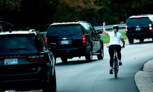 واکنش معترضانه یک بانوی دوچرخه سوار آمریکایی به کاروان خودرویی حامل ترامپ در نزدیکی باشگاه گلف ترامپ در ویرجینیا  