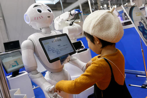 بازی یک کودک با روبات انسان نمای سافت بانک ژاپن ( به نام پِپِر) در نمایشگاه سالانه روبات در توکیو