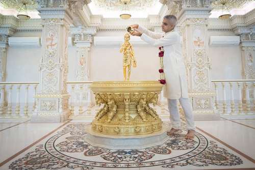 شهردار لندن در حال ریختن آب مقدس روی مجسمه ای طلایی در معبدی در دهلی نو هند