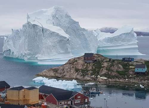 عبور یک کوه یخ شناور از کنار جزیره‌ای در گرینلند/ رویترز