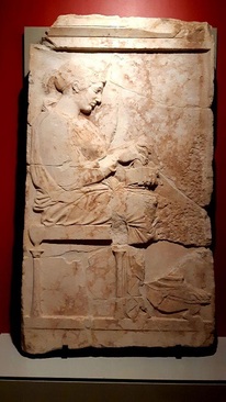 سنگ مزار با نام فیلیس/ جزیره تاسوس(یونان)، حدود 440-450 پیش میلاد/ مرمر تاسوس، حاصل از ماموریت کاوش امانوئل میلر،1865 میلادی/ سنگ مزار بزرگ با تصویر بانوی متوفی،«فیلیس، دختر کلئوکن» بر اساس کتیبۀ موجود بر ان. دختر جوان روی چهارپایه نشسته، با پیراهنی کوتاه و بالاپوش ضخیم و چین‌دار روی آن و جعبه‌ای در دست راست او. بر اساس سبک اثر، مربوط به دورۀ خلق حاشیه‌های تزئینی معبد پارتنون در شهر آتن، کشف شده در سال 1862 در جزیره تاسوس(شمال یونان)، مقارن افزایش کاوش‌های باستان‌شناسان فرانسوی در حوزۀ مدیترانه است.