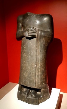 مجسمۀ گودِآ/ دوران نو-سومری، دوره حکمرانی گودِآ حدود 2120 پیش میلادی./ سنگ گابرو، کاوش‌های ارنست دوسارزک،1881 میلادی/ گودِآ شاهزاده سومری، در حالت ایستاده و با دست‌های به حالت دعا، بدون زیورآلات در هیئت پادشاهی با تقوا که دستور بازسازی معابد شهرش را داده بود. از کاووش‌های ارنست دو سارزک در تللو که به کشف تمدن سومری و تاسیس دپارتمان ویژه برای آثار باستانی شرقی در موزۀ لوور در سال 1881 منجر شد.
