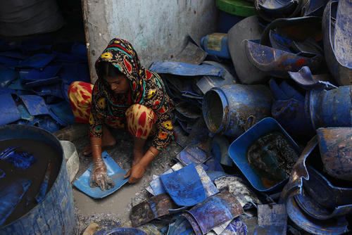 زن کارگر در حال تمیز کردن پلاستیک‌ها در یک کارخانه بازیافت پلاستیک در حومه شهر داکا بنگلادش