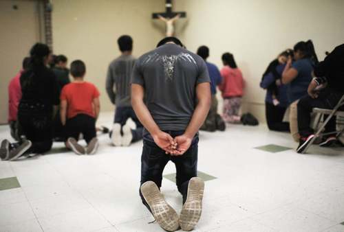 مهاجران غیرقانونی در حال دعا در یک مرکز نگهداری از صدها مهاجر غیرقانونی وارد شده به آمریکا در 