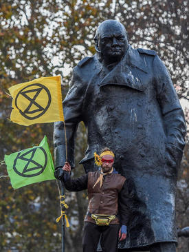 تظاهرات حامیان محیط زیست در لندن. یک فعال محیط زیست در کنار مجسمه وینستون چرچیل در مقابل پارلمان بریتانیا در 