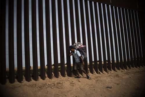 یک مهاجر از کشورهای آمریکای مرکزی در حصار مرزی بین مکزیک و ایالت کالیفرنیا آمریکا/ خبرگزاری فرانسه