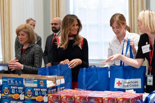 ملانیا ترامپ بانوی اول آمریکا در حال کمک به بسته‌بندی اقلام ارسالی صلیب سرخ آمریکا برای سربازان این کشور