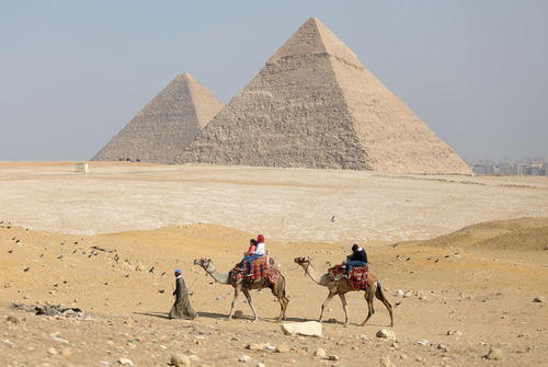 بازدید گردشگران بر روی شتر از اهرام ثلاثه مصر