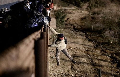 تلاش یک مهاجر برای عبور از مانع مرزی مکزیک و ایالات متحده آمریکا/ خبرگزاری فرانسه
