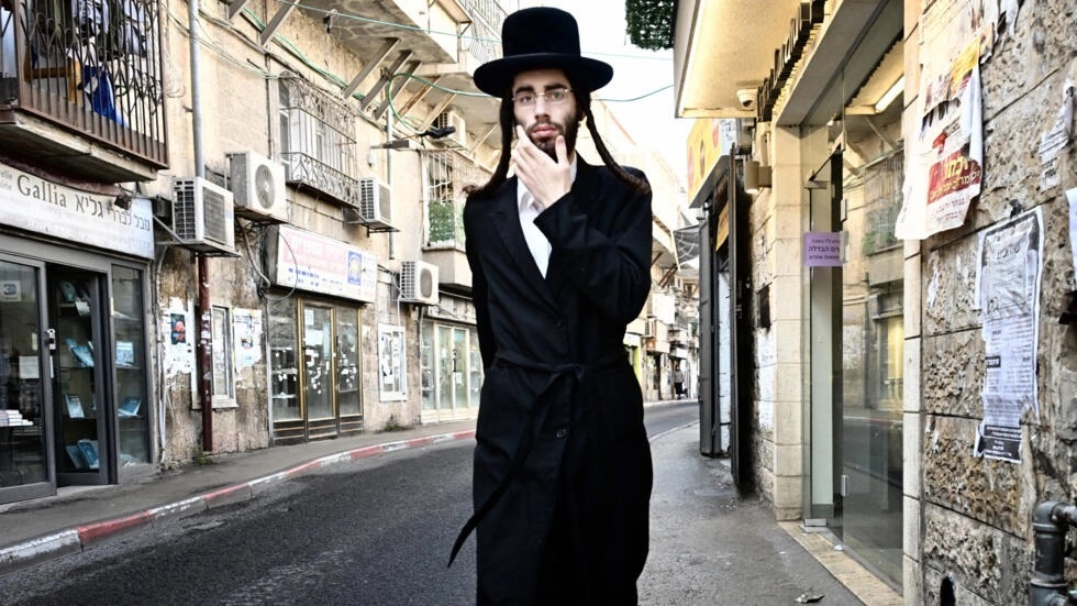 عکس - یک مرد یهودی افراطی مذهبی در 2 ژانویه 2024 در محله یهودیان مذهبی Mea Shearim در شهر قدس/ اورشلیم قدم می زند.خبرگزاری فرانسه
