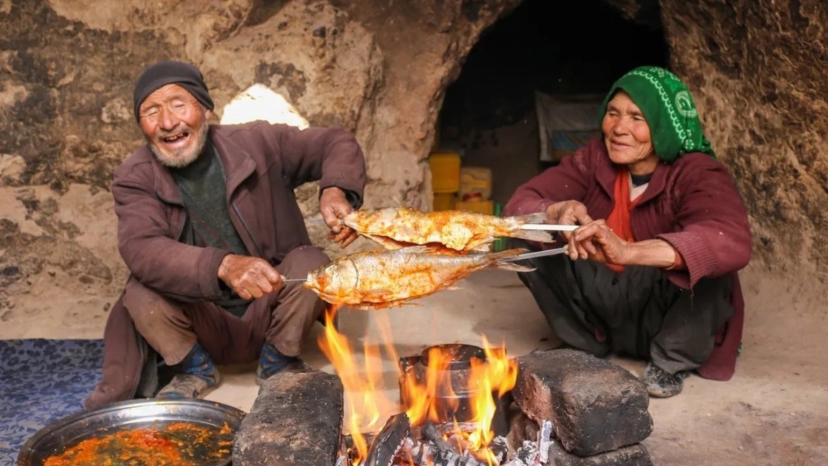 کباب کردن ماهی روی زغال توسط زوج غارنشین افغان (فیلم)