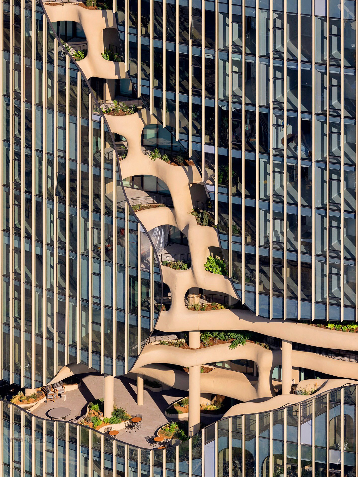 نمای ساختمان وان ریور نورث در دنور با نمای شیشه‌ای و شکاف عمیق صخره‌ای مجهز به گیاهان طبیعی و مسیر پیاده‌روی عمودی.