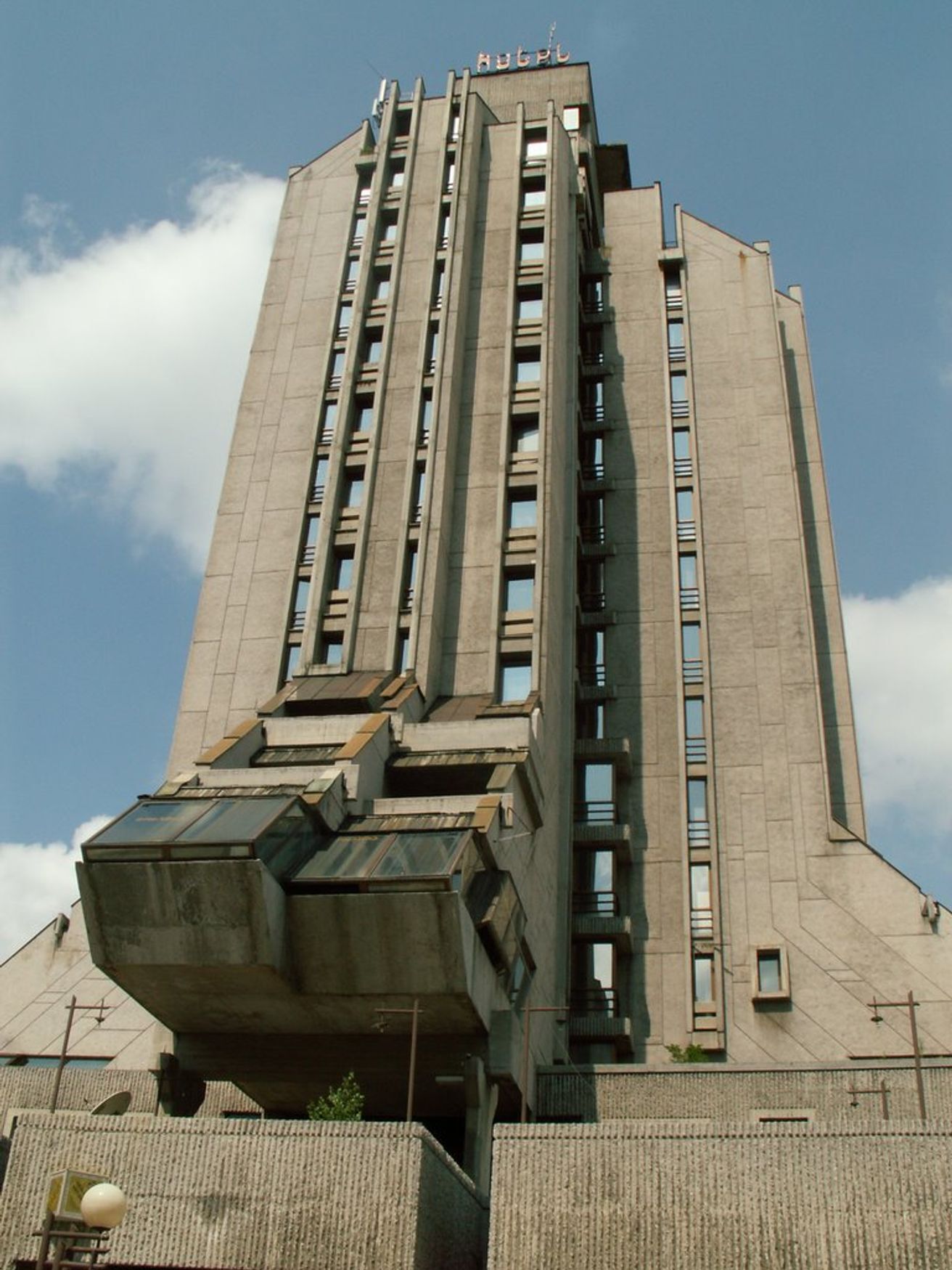 تصویر هوایی پهپاد از ساختمان بتنی و عظیم هتل زلاتیبور در صربستان با معماری بروتالیست و نمایی از مرکز شهر اوژیتسه.