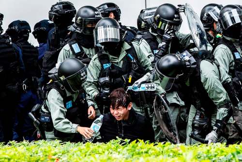 پلیس هنگ کنگ در حال شستشوی صورت معترضی که پیش از دستگیری به روی او گاز فلفل پاشیده است./ خبرگزاری فرانسه