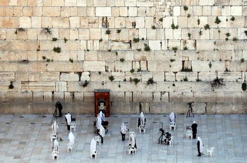 تعداد انگشت شماری از نمازگزاران یهودی در حال نماز خواندن در دیوار غربی در شهر قدس در روز عید پاک. هر ساله در این مراسم هزاران یهودی گردهم می‌آمدند اما امسال به دلیل بحران کرونا این مراسم لغو شد./ رویترز