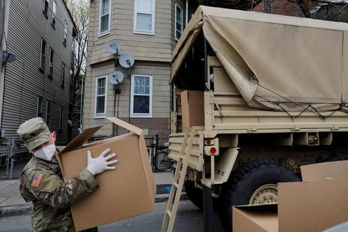 نیروی گارد ملی آمریکا در حال تخلیه کامیون حامل مواد غذایی برای توزیع در یک مرکز در شهر 