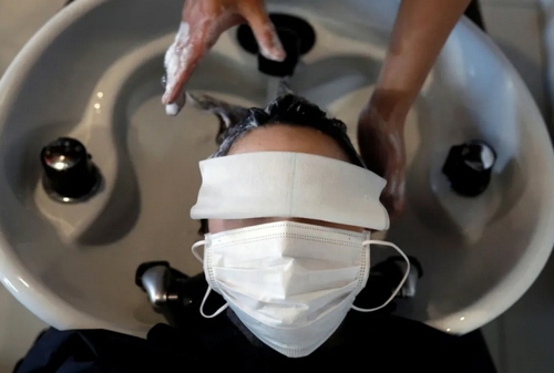 شستشوی موی یک مشتری در آرایشگاهی در شهر توکیو. آرایشگاه های ژاپن موظف شده‌اند به مشتریان خود نوبت‌های تکی بدهند تا در محل آرایشگاه ازدحام ایجاد نشود./ رویترز