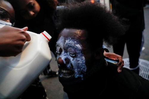 ریختن شیر به صورت یک معترض برای کم کردن اثر گاز اشک‌آور در جریان تظاهرات بر ضد قتل 