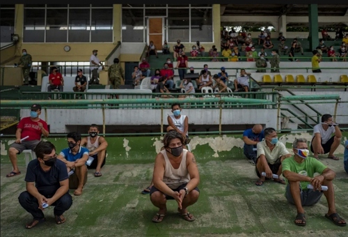دستگیری فیلیپینی‌ها به دلیل نزدن ماسک. پس از دستگیری این افراد به استادیوم منتقل شده و به آنها ماسک داده شده است./ گتی ایمجز