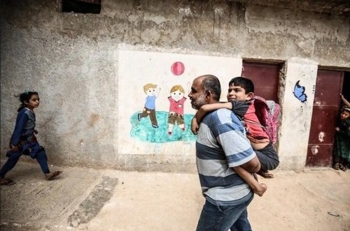 یک پدر سوری در حال بُردن فرزند معلولش به مدرسه در 