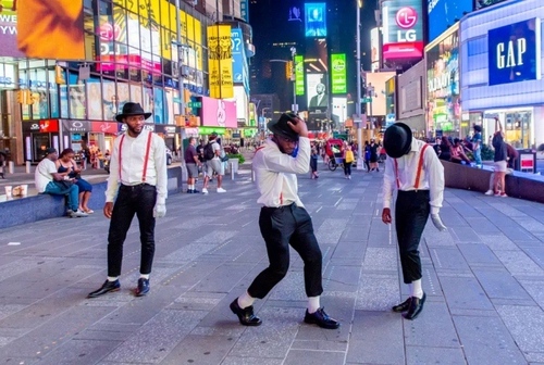 3 مرد رقصنده در حال اجرای برنامه در میدان تایمز نیویورک. این 3 مرد در حال اجرای رقص به سبک 