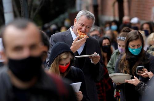 شهردار دموکرات شهر نیویورک آمریکا در حال خوردن پیتزا و در انتظار رای دادن در صف رای‌گیری زودهنگام در انتخابات ریاست جمهوری / رویترز