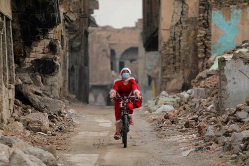 زن عراقی در لباس بابانوئل در حال دوچرخه‌سواری در ویرانه‌های جنگ در بخش قدیمی شهر موصل/ رویترز