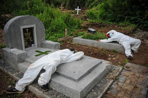 استراحت کارمندان گورستانی در باندونگ اندونزی پس از دفن یک فوتی کرونا/ رویترز