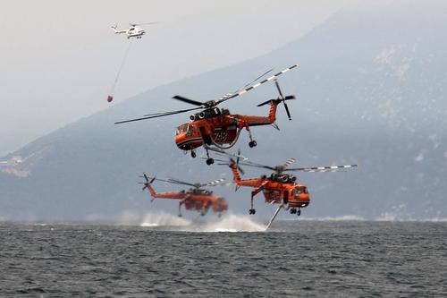 هلی کوپترهای آتش نشان در حال پر کردن آب از دریا برای خاموش کردن آتش سوزی های جنگلی مهیب در جزیره 