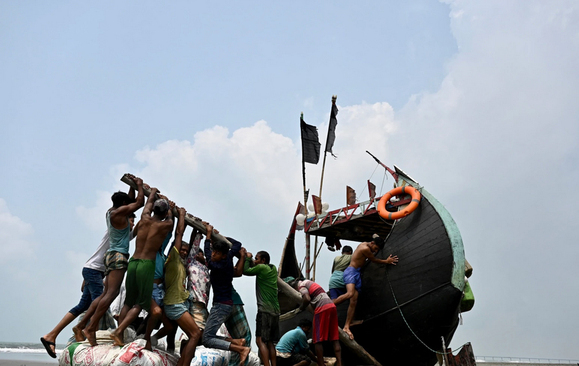 تلاش برای تکان دادن یک قایق ماهیگیری به گِل نشسته در خلیج بنگال/ خبرگزاری فرانسه