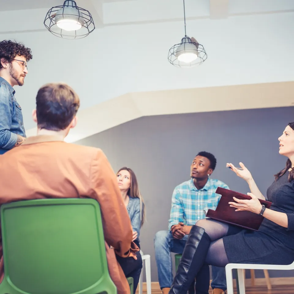 فردی با اعتماد به نفس در جمع صحبت می‌کند و دیگران به او گوش می‌دهند